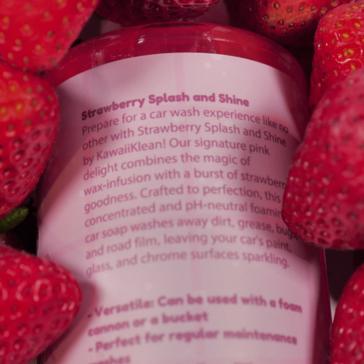 16 oz bottle of 'Strawberry Splash and Shine' pink car soap, detailed description visible, nestled among fresh strawberries, highlighting the soap's natural strawberry essence and vibrant cleaning power.